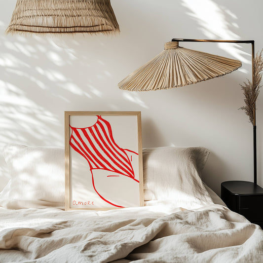 Framed artwork with red design on a bed in a room with natural light
