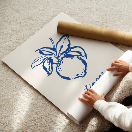 Person unrolling a large sheet of paper with blue lemon design on a light-colored floor.