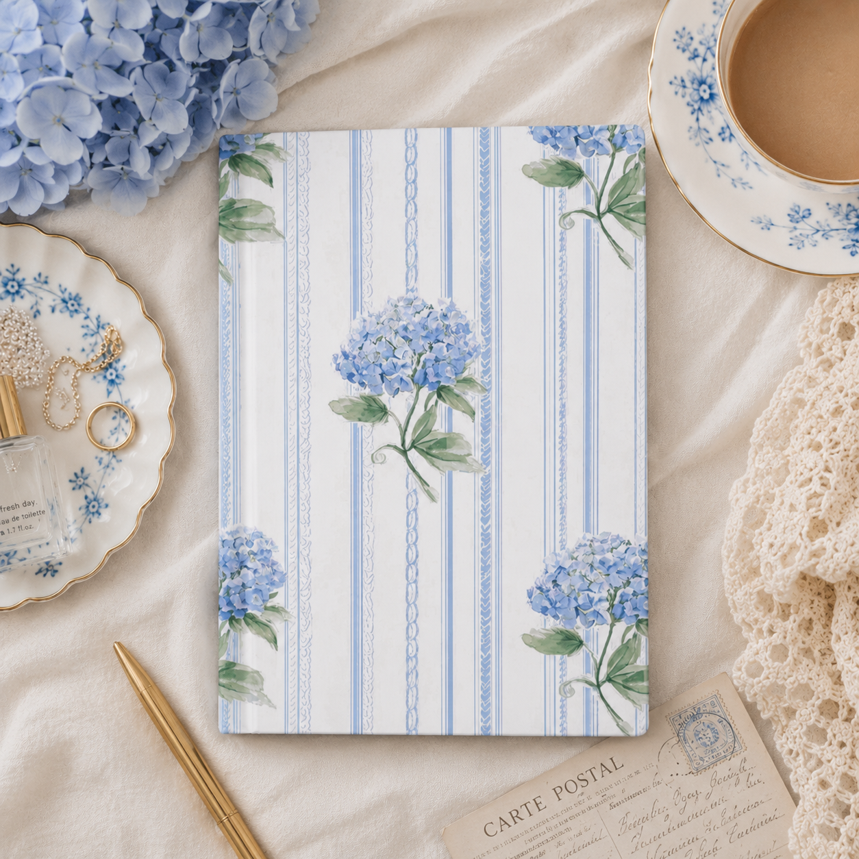 Elegant hardcover hydrangea journal with soft blue floral artwork styled in a romantic stationery flatlay.