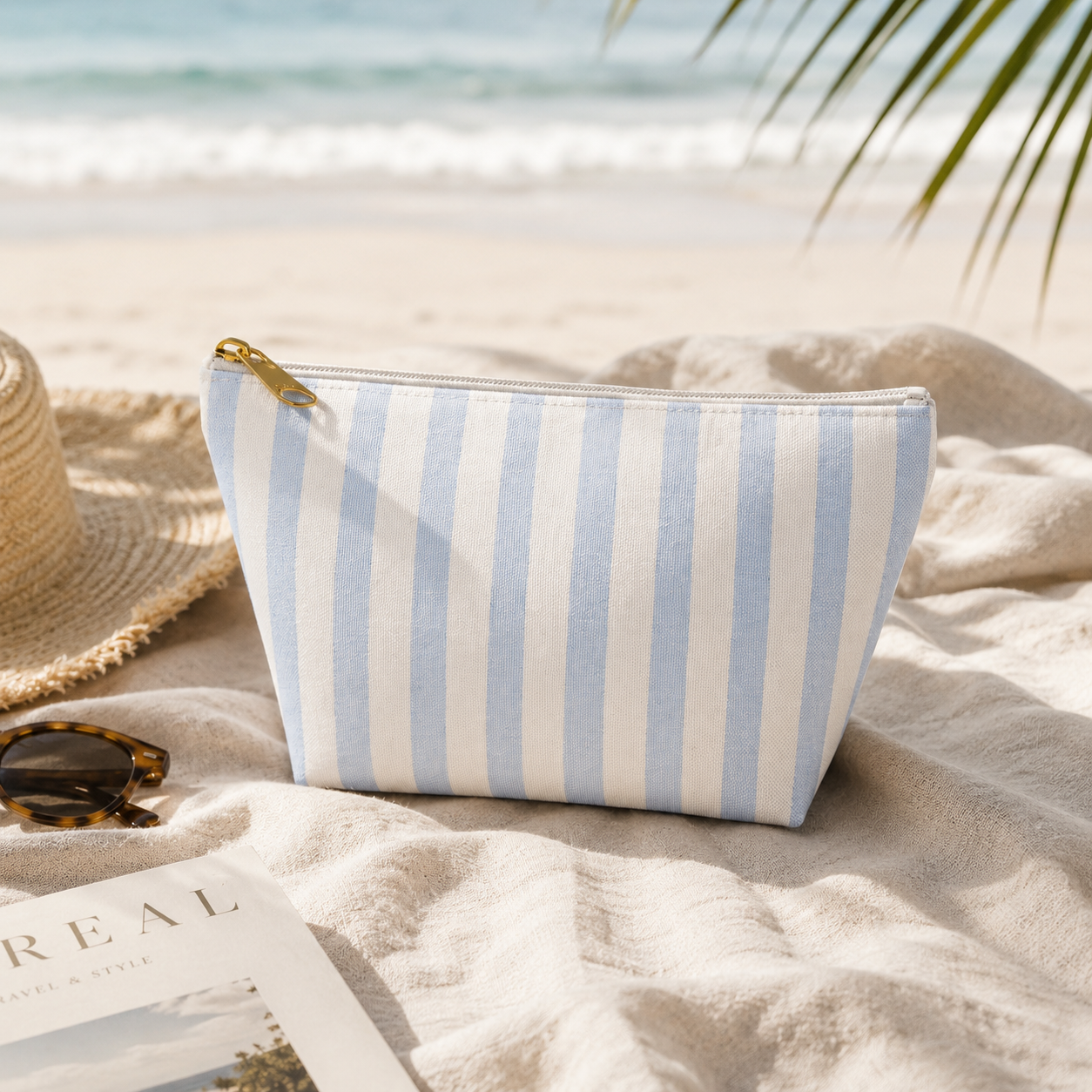 Striped beach bag on a sandy beach with sunglasses and a hat