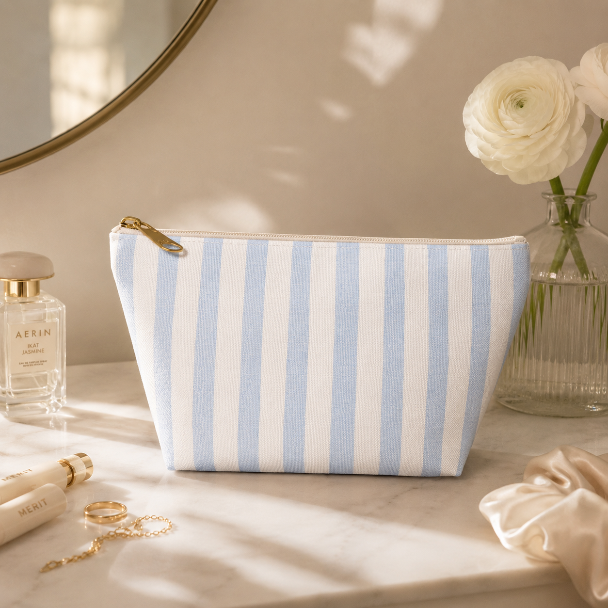 Striped makeup bag on a vanity with perfume and flowers