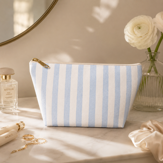 Striped makeup bag on a vanity with perfume and flowers