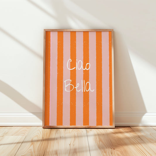 Framed artwork with 'Ciao Bella' text on a striped background in a room with wooden floor and white walls.