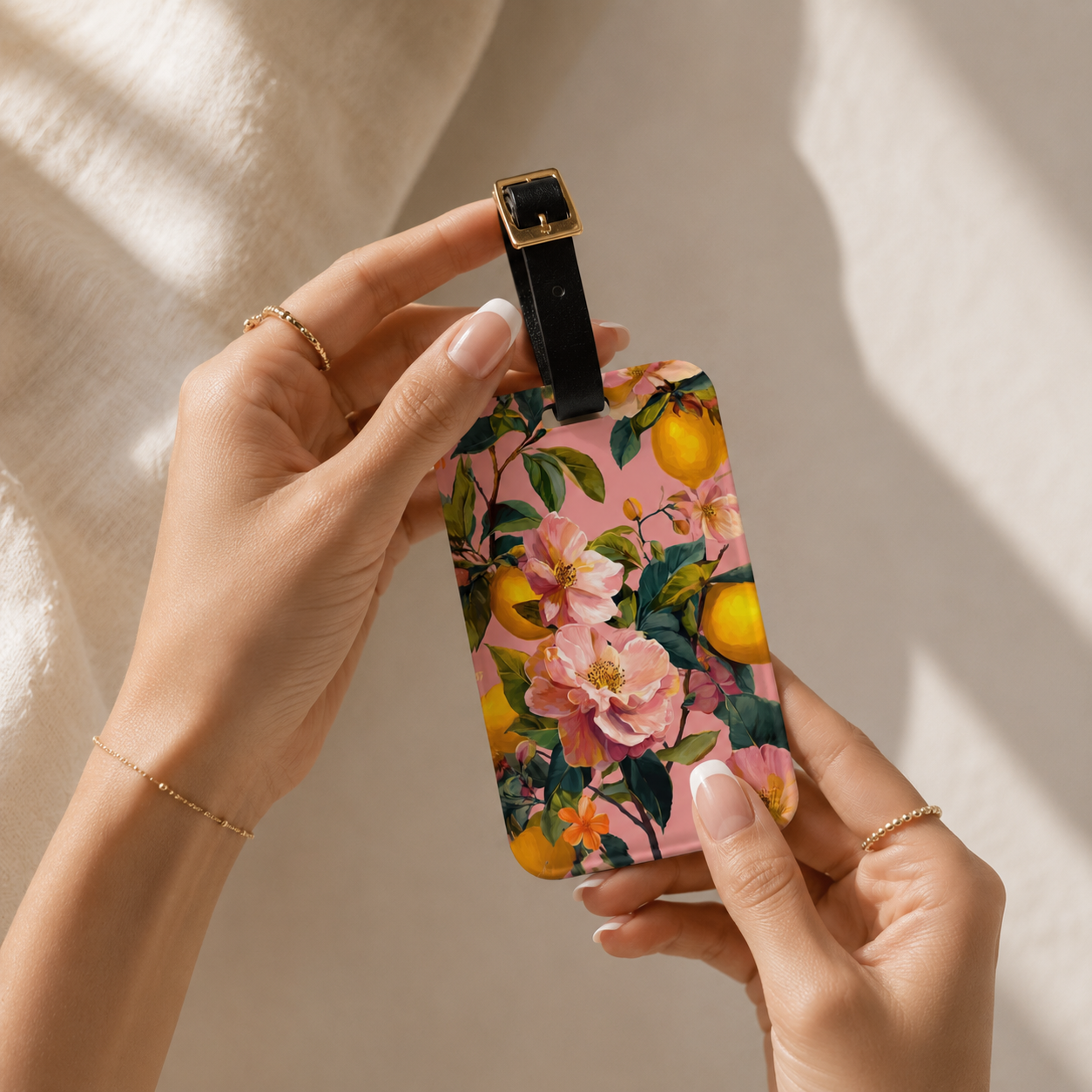 Hand holding a floral lemon luggage tag with fruits on a neutral background
