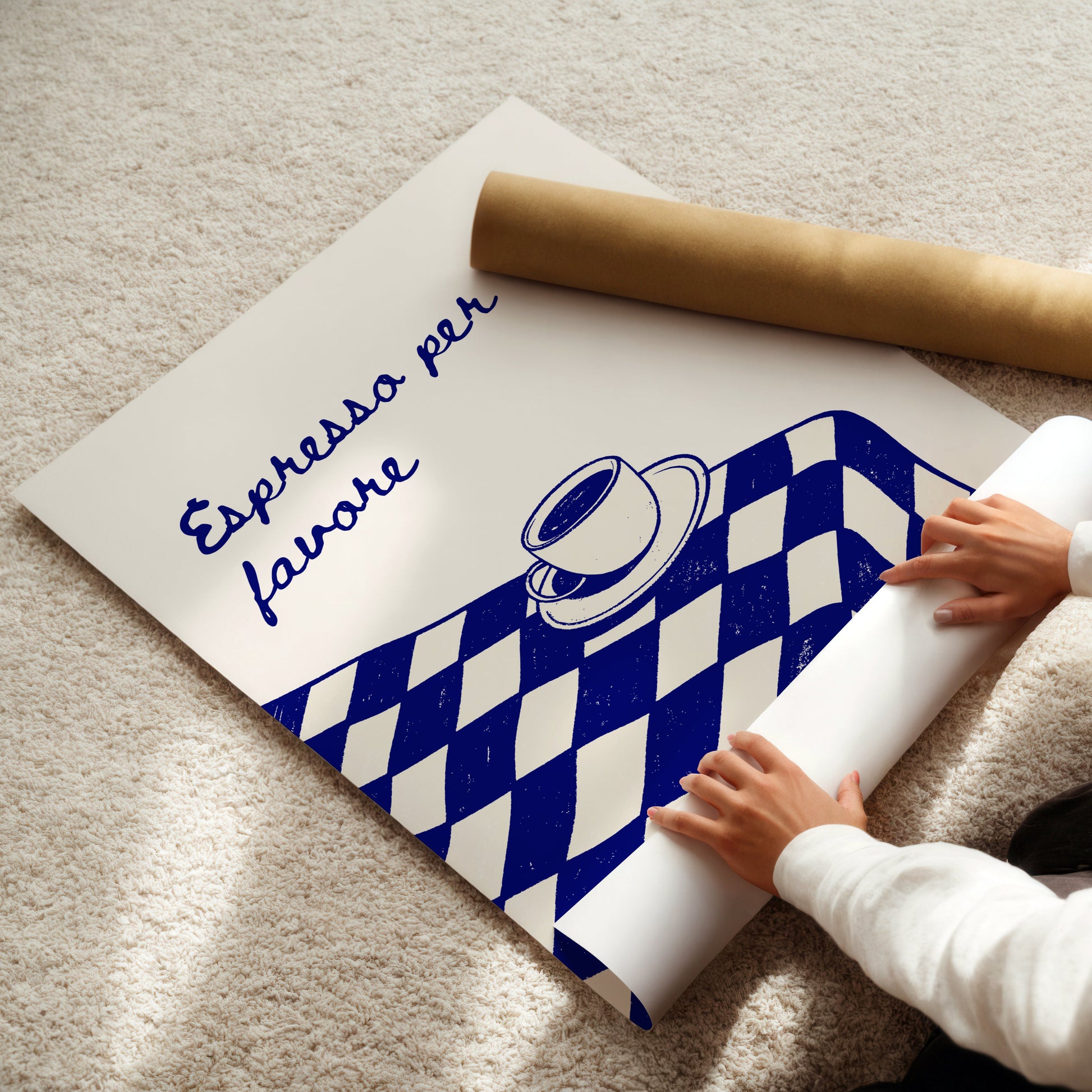 Person unrolling a poster with a coffee-themed design on a light-colored floor.