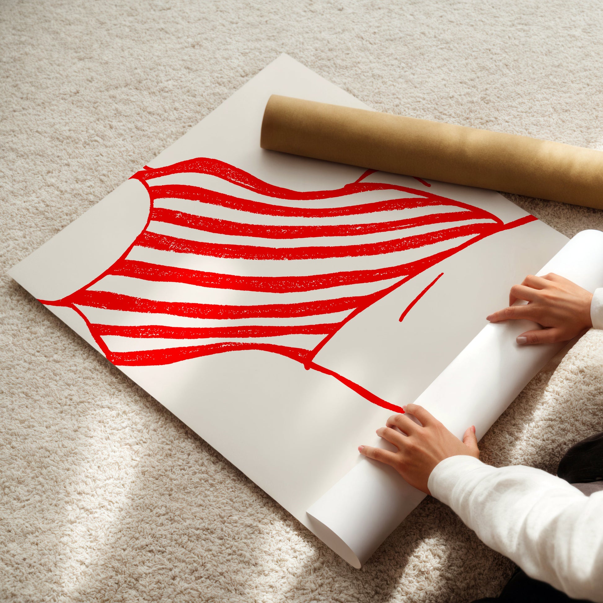Person unrolling a large poster with red and white female body and swimsuit design on a beige carpet