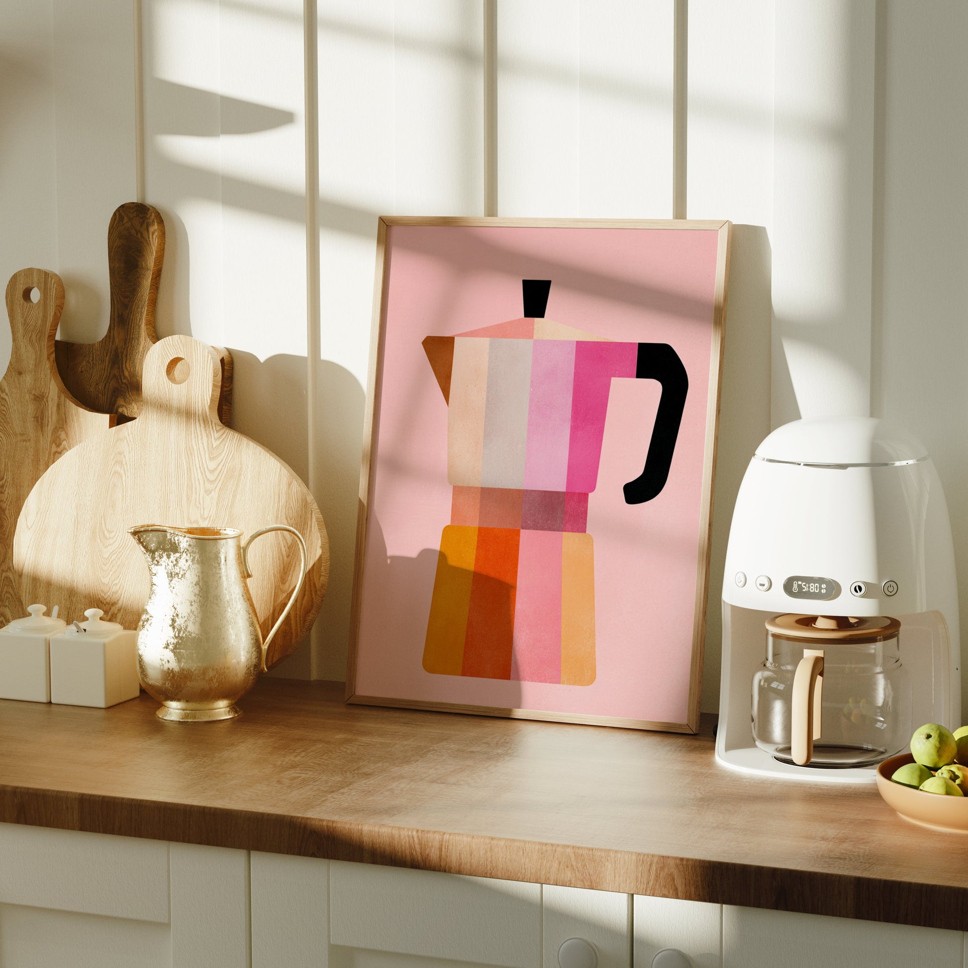 Kitchen counter with a coffee machine, bowl of fruit, and abstract art on a wooden surface.