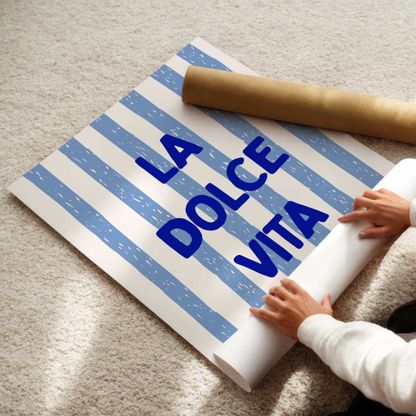 Person unrolling a poster with 'La Dolce Vita' text on a carpeted floor