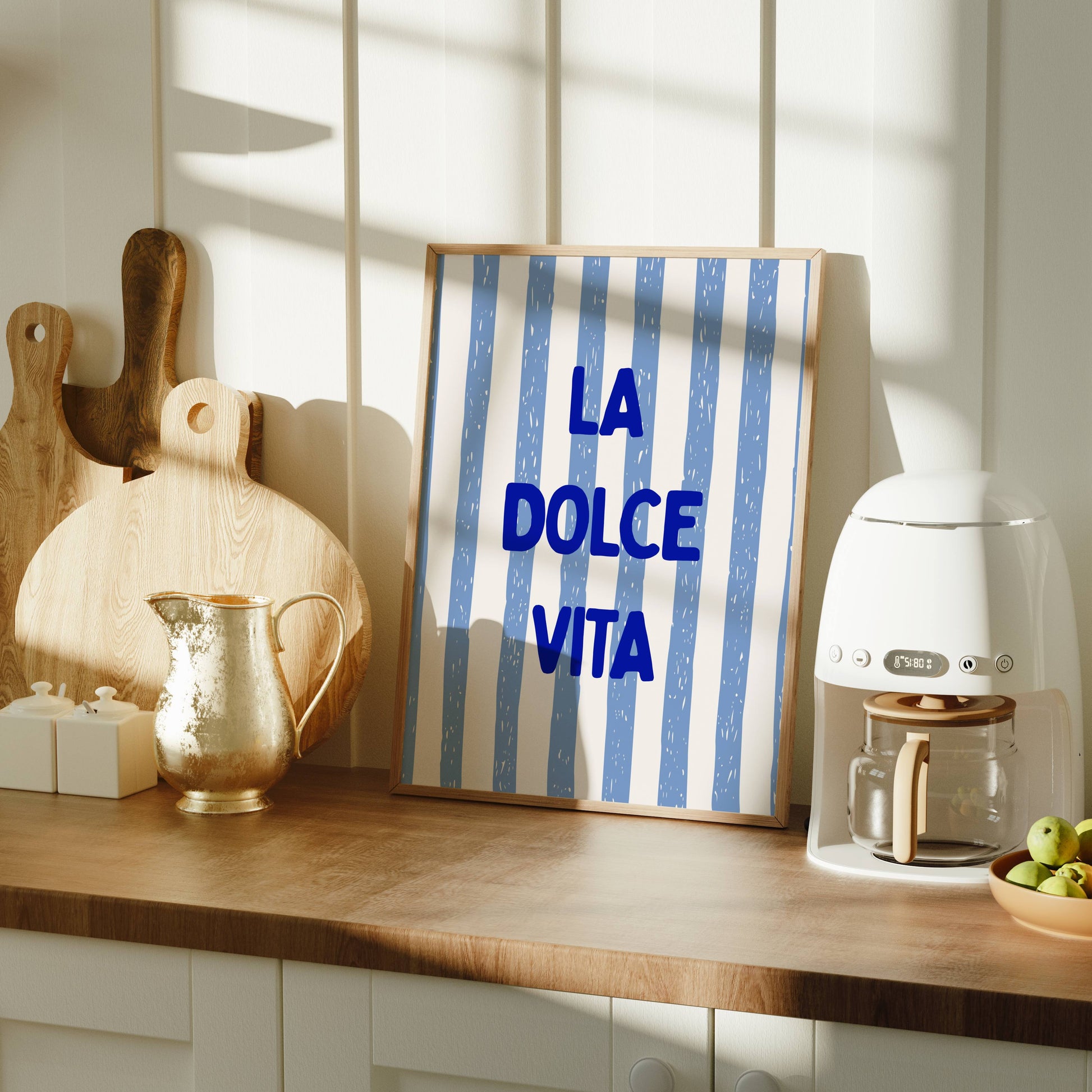 Kitchen counter with a coffee machine, 'La Dolce Vita' sign, and fruit bowl.