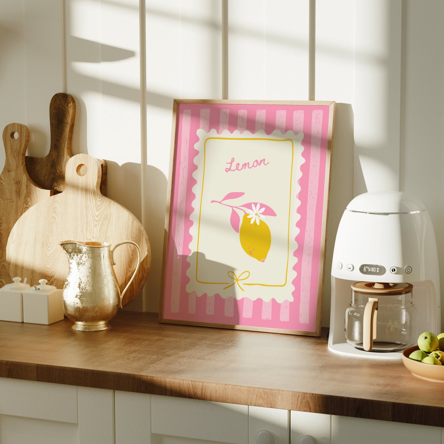 Kitchen counter with a coffee machine, bowl of fruit, and framed picture on a wooden surface.