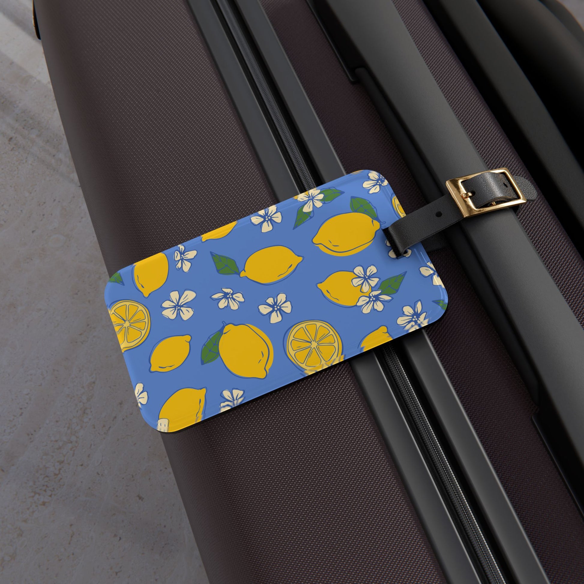 Luggage tag with lemon pattern attached to a suitcase