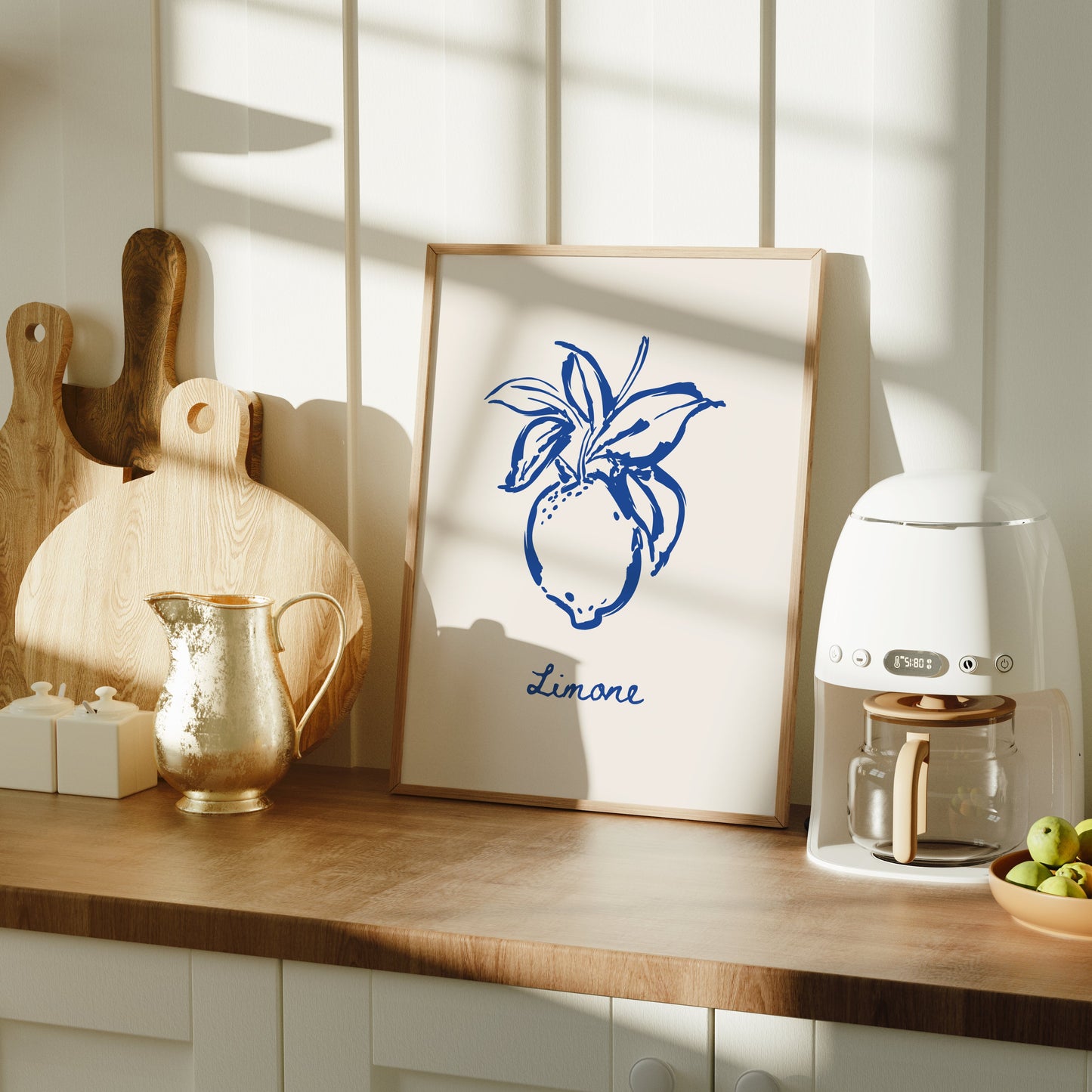 Kitchen counter with a framed lemon artwork, coffee machine, and fruit bowl.