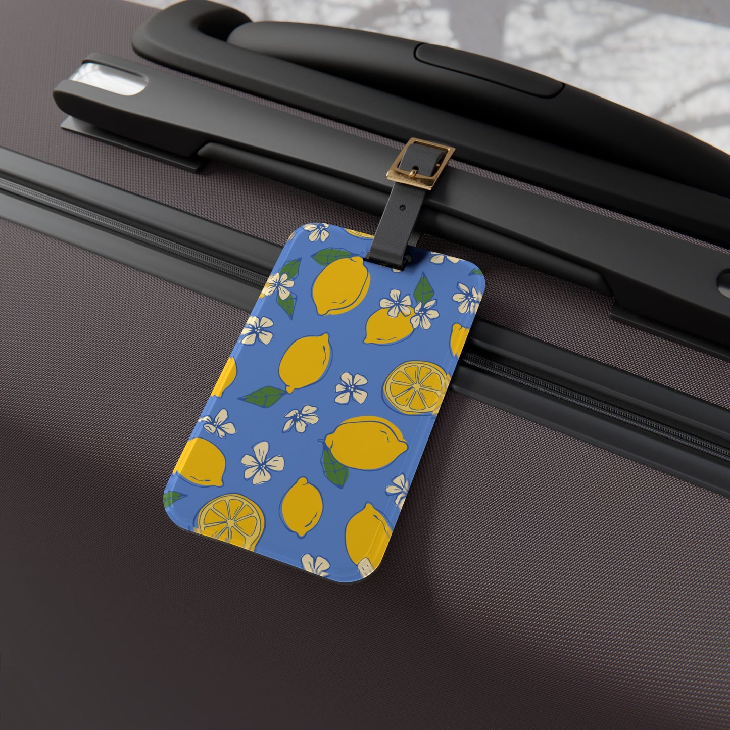 Luggage tag with lemon pattern attached to a suitcase
