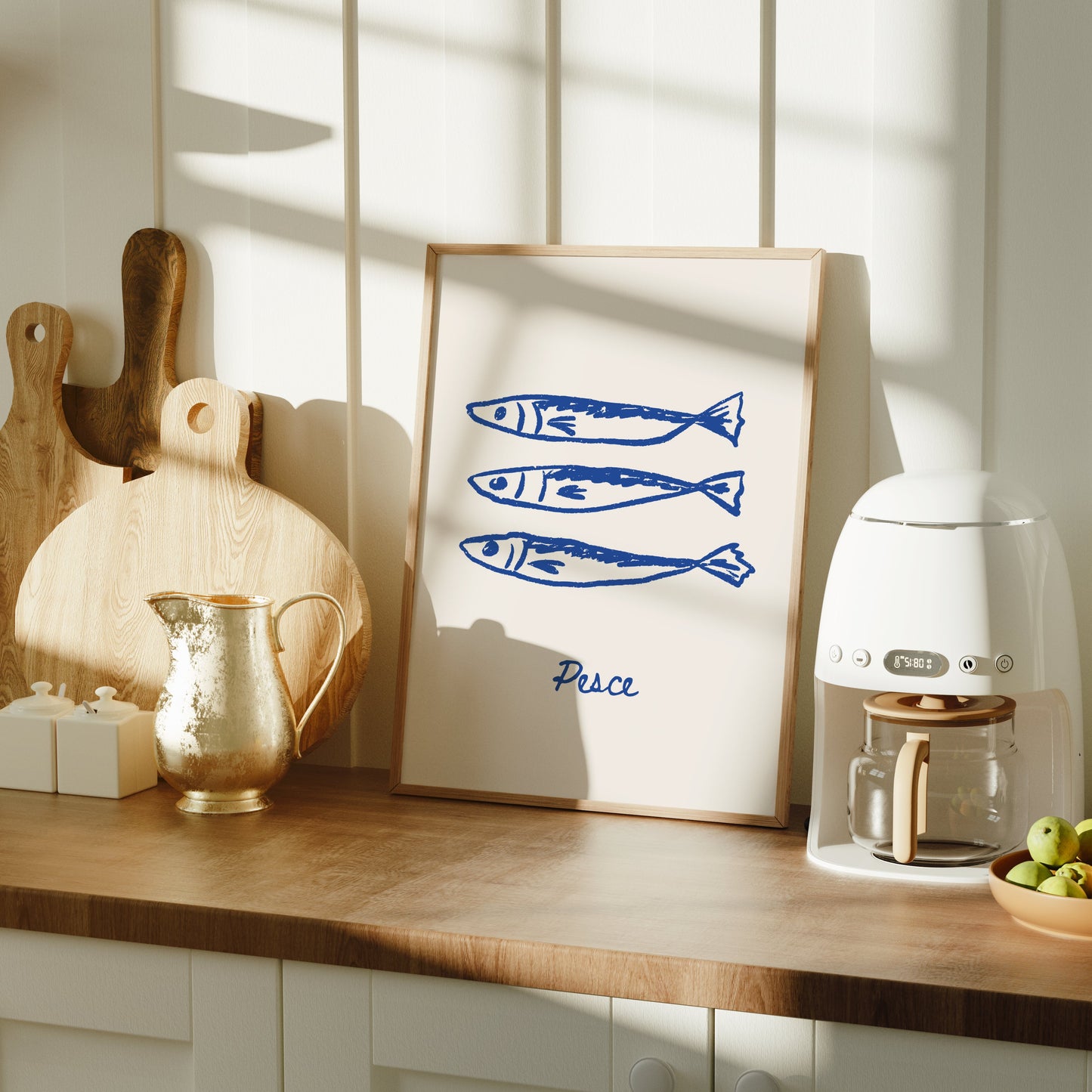 Kitchen counter with a coffee machine, cutting boards, and a framed picture of fish.