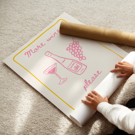 Person unrolling a poster with wine-themed design on a carpeted floor