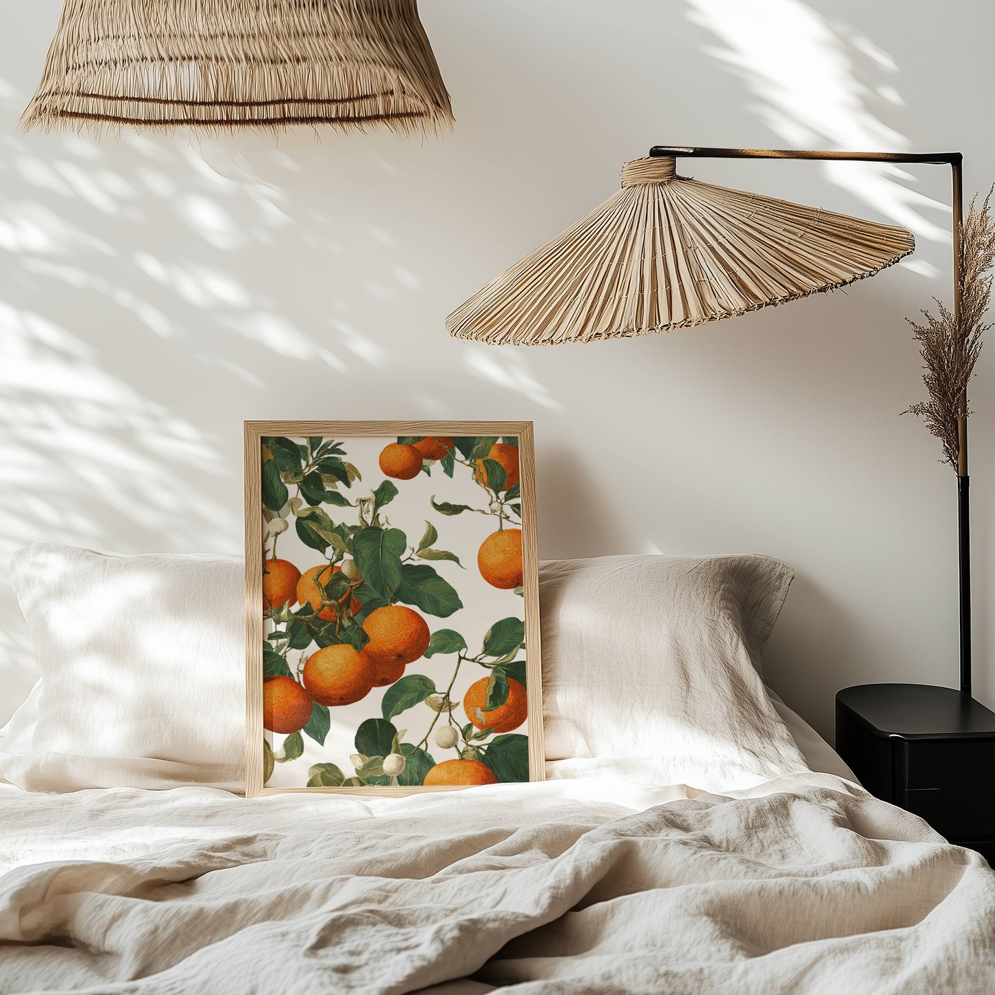 Framed artwork of oranges on a bed with wicker lamps and a neutral color scheme.