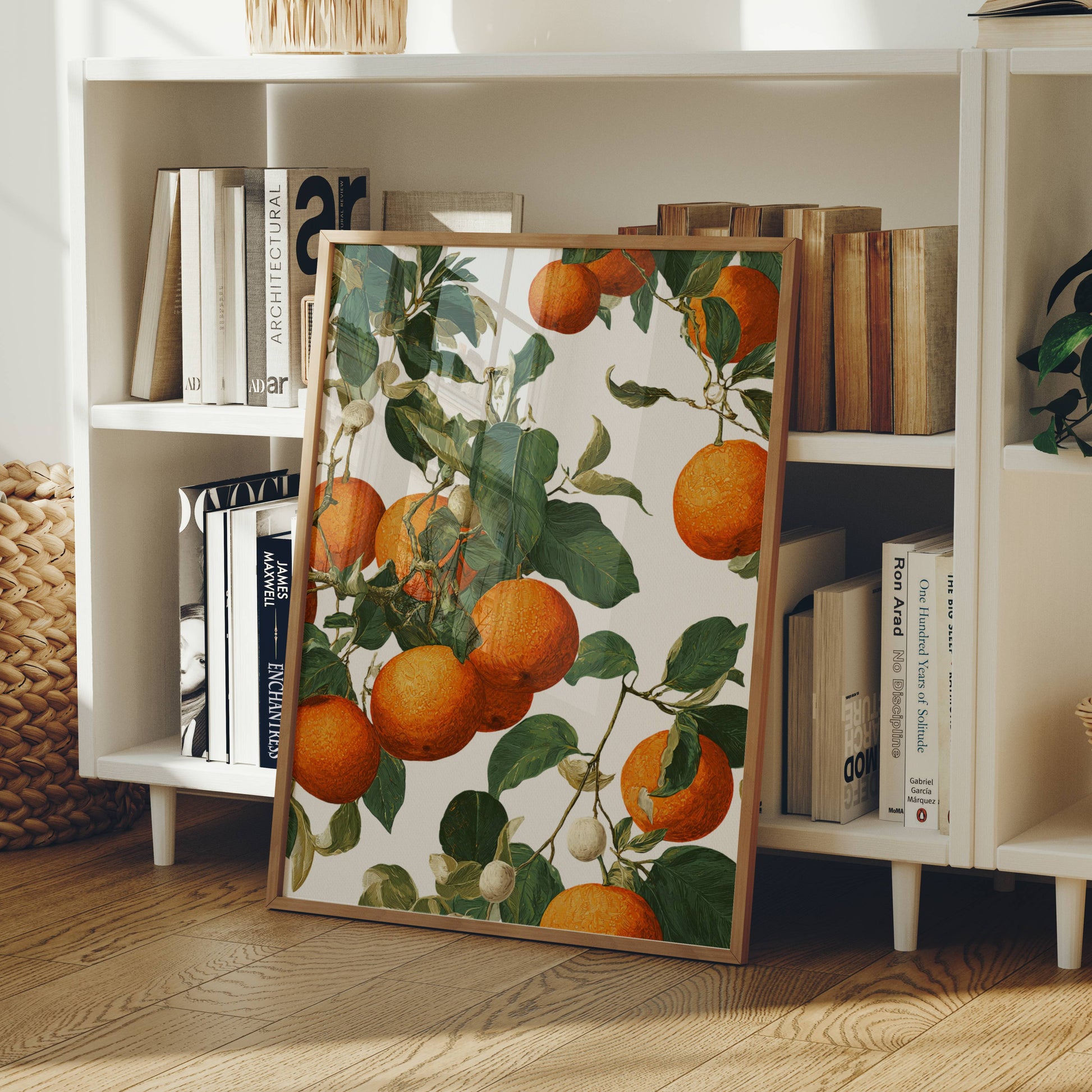 Framed artwork of oranges and green leaves on a bookshelf background