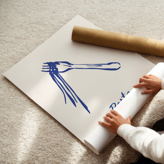 Person unrolling a large poster with blue pasta artwork on a beige carpet