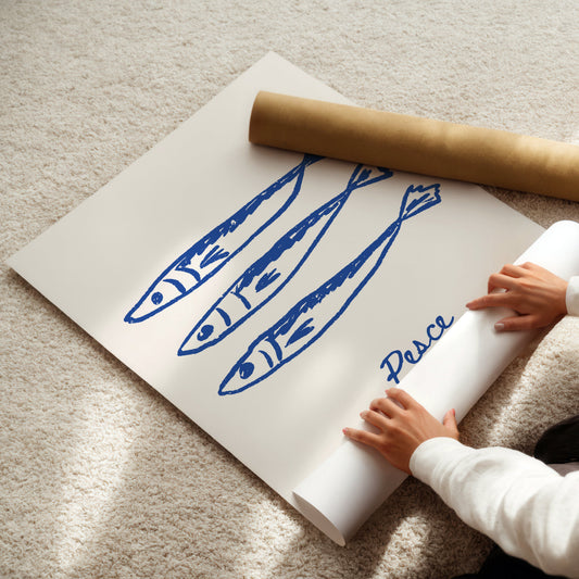 Person unrolling a poster with blue fish illustrations and the word 'Pesce' on a light-colored floor.
