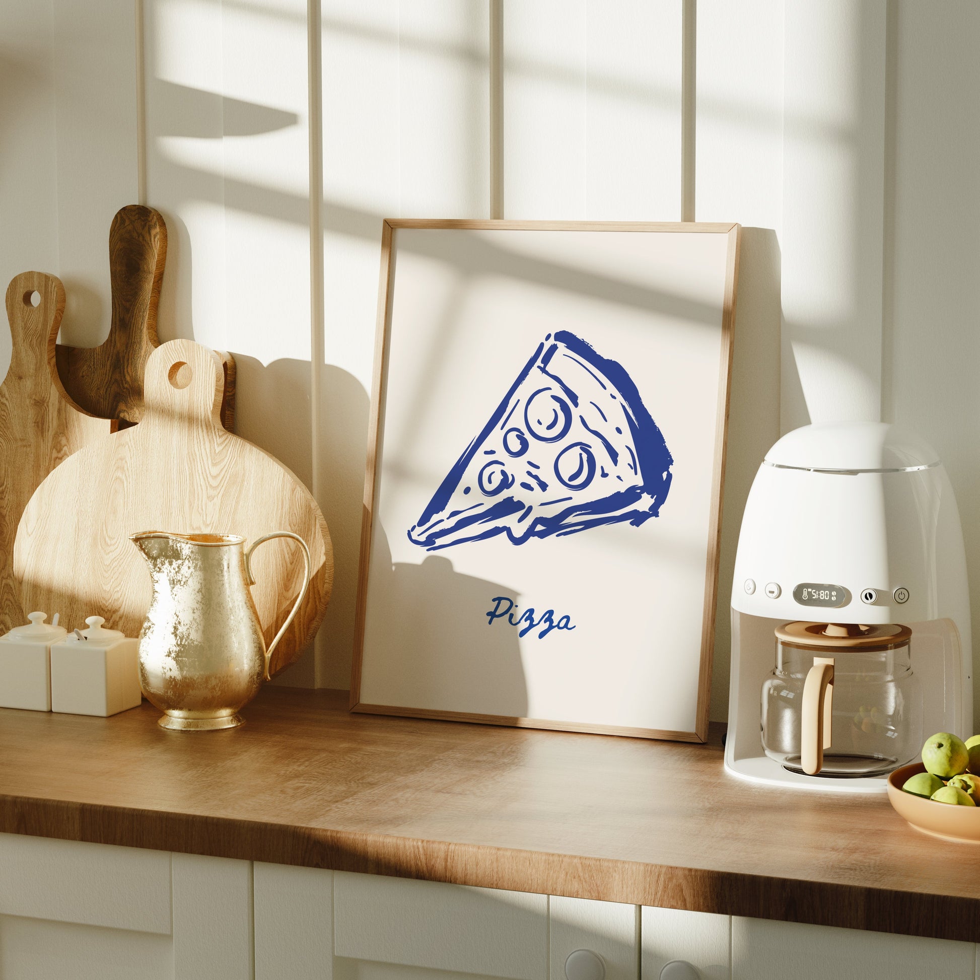Kitchen counter with a framed picture of a pizza slice, coffee machine, and fruit bowl.
