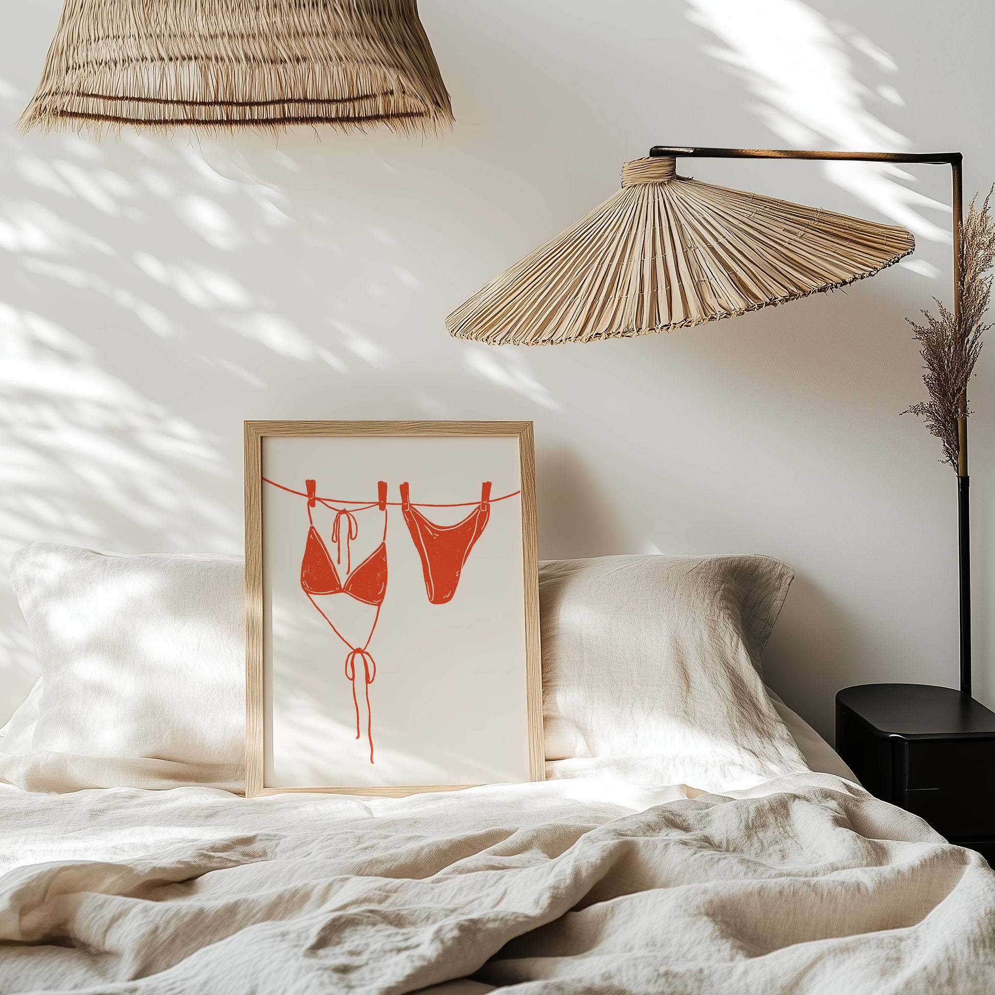 Framed artwork of red bikini on a bed with wicker lamps and white bedding