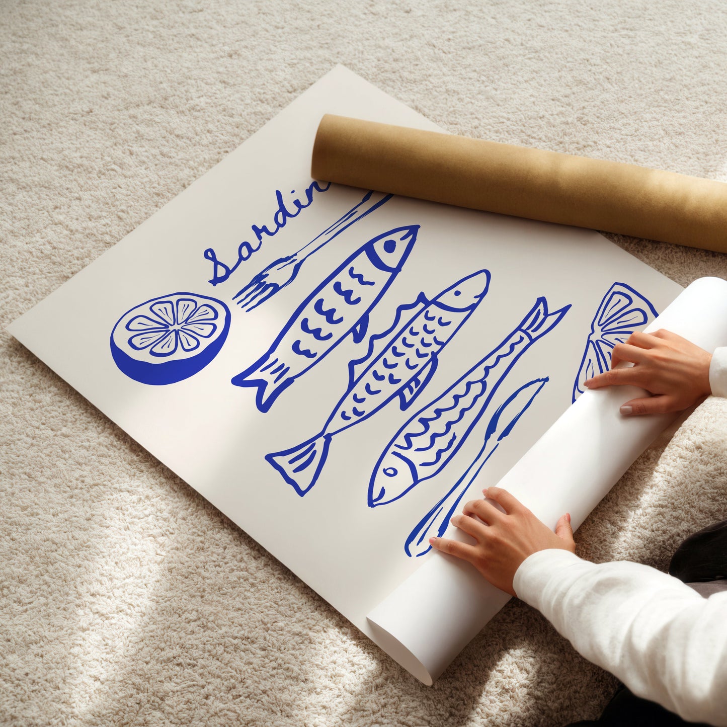 Person unrolling a poster with blue fish illustrations on a beige carpet