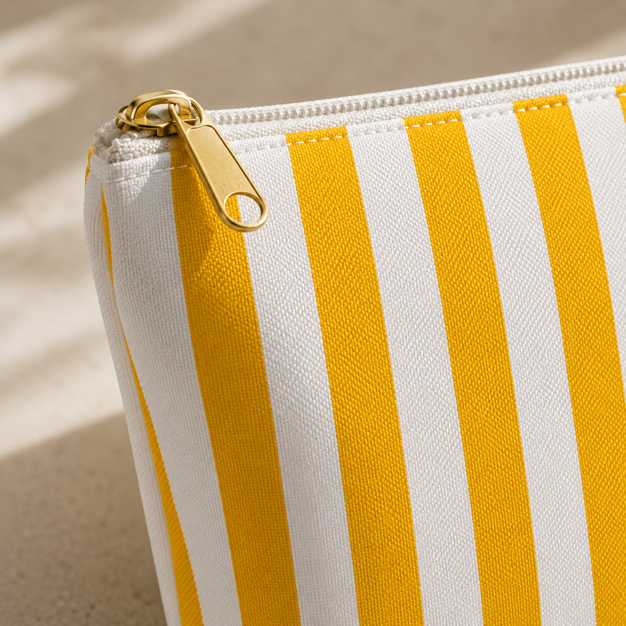 Striped pouch with gold zipper on a beige background